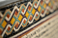Intricate patterned tile featuring vibrant orange, yellow, and blue hues — a decorative element with geometric designs