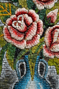 Vibrant mosaic art featuring pink roses in a blue vase — intricate tile design with rich colors and textures