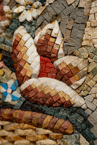 Intricate mosaic art featuring vibrant red and earthy tones — floral design crafted from small stone tiles.