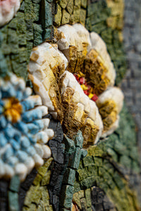Intricate mosaic art featuring vibrant flowers in textured stone — showcasing detailed craftsmanship with vivid colors.