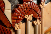 Intricate decorative wall art featuring terracotta and cream stone in a geometric design with textured details