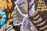 Intricate mosaic artwork featuring vibrant purple and earthy tones—textured tiles create a stunning visual depth.