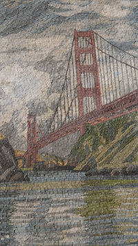 Intricate mosaic artwork depicting the Golden Gate Bridge with textured stone tiles in varying shades of red and grey.