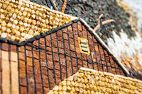 Textured mosaic artwork featuring a rustic barn in warm earthy tones with intricate stone detailing and layered patterns.