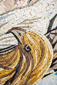 Intricate mosaic art featuring a detailed golden bird design — crafted from various textured tiles in warm tones.