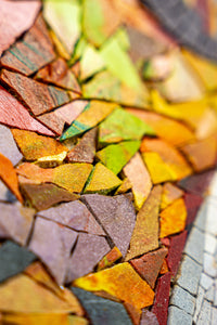 Vibrant mosaic art featuring a mix of colorful tiles in shades of orange, green, and purple with a textured finish