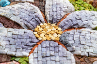 Intricate mosaic flower design featuring textured tiles in shades of purple, brown, and yellow — a vibrant artistic display