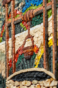 Intricate mosaic artwork featuring vibrant colors and textured stones, showcasing a rustic basket motif against a natural backdrop.