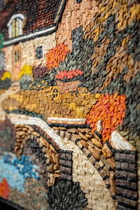 Intricate mosaic artwork depicting a quaint cottage surrounded by vibrant autumn foliage and a winding stone pathway