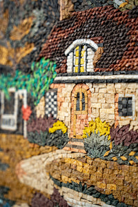 Intricate mosaic artwork depicting a charming cottage surrounded by vibrant foliage — detailed textures and warm colors create depth.