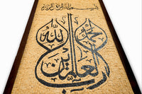 Intricate calligraphy art piece on textured beige background — featuring elegant Arabic script in bold black design