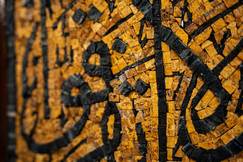 Intricate mosaic artwork featuring golden and black tiles, showcasing a stunning blend of craftsmanship and design.