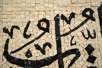 Intricate mosaic artwork featuring black and beige tiles arranged in a flowing script pattern — a stunning display of craftsmanship.