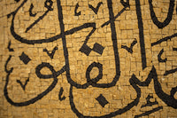 Intricate mosaic art featuring Arabic calligraphy in rich brown tones on a textured beige background — a stunning cultural piece.