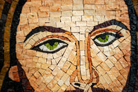 Intricate mosaic artwork featuring a close-up of a face with striking green eyes and textured stone tiles in earthy tones