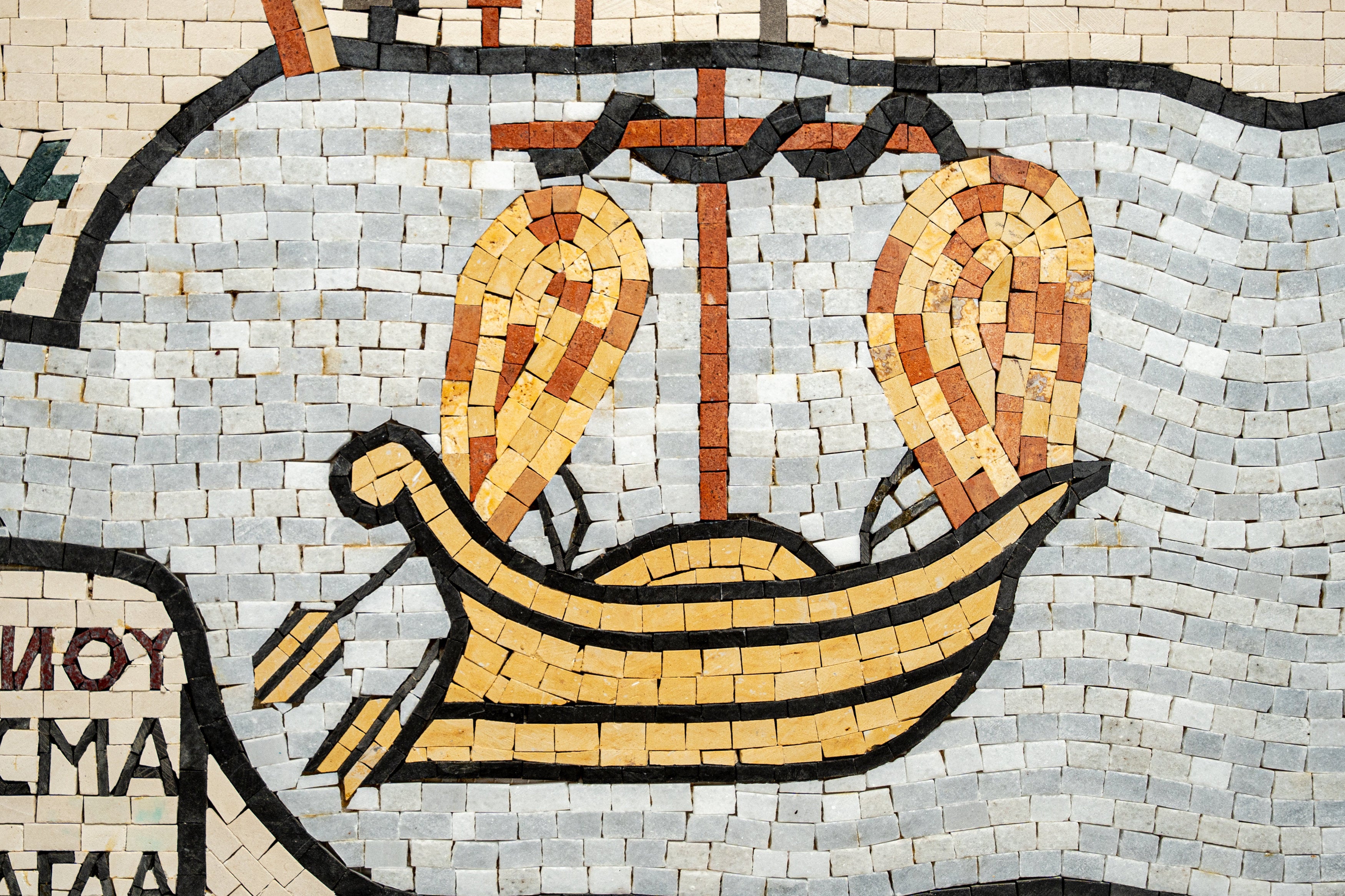 Intricate mosaic artwork featuring a yellow boat with oars against a textured grey background — a blend of artistic craftsmanship.