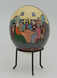 Intricate decorative egg featuring the Last Supper scene in vibrant colors — a unique piece of folk art on a metal stand