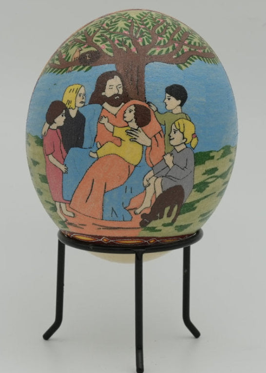 Intricately painted decorative egg featuring a family scene under a tree — vibrant colors and detailed imagery enhance its charm.