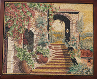 Intricate tapestry wall art depicting a scenic garden pathway with vibrant floral details and a rustic archway.