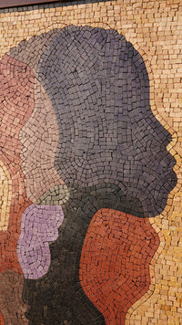 Stylized mosaic wall art featuring abstract profiles in earthy tones — a blend of textured bricks creating depth.