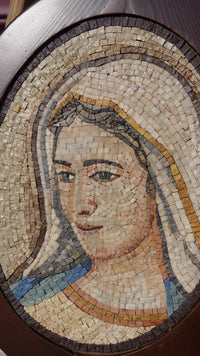 Intricate mosaic art depicting a serene face with a soft expression — crafted from natural stone tiles in warm hues.