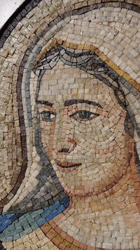 Intricate mosaic artwork depicting a serene face with soft hues of beige and blue — crafted from natural stone tiles.