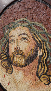 Intricate mosaic artwork depicting a serene face with flowing hair, crafted from natural stone tiles in earthy tones.