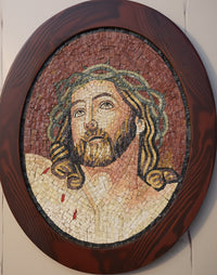 Intricate mosaic artwork depicting a serene figure with flowing hair and a detailed beard, framed in a rich wooden oval.
