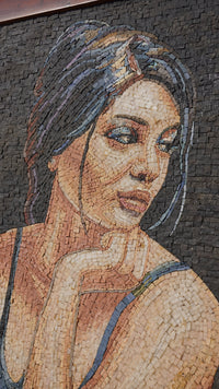 Intricate mosaic portrait art featuring a woman with flowing hair and thoughtful expression — composed of varied stone tiles.