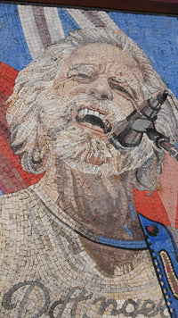 Vibrant mosaic mural depicting a singer with long hair and a microphone, capturing a moment of musical passion and expression.
