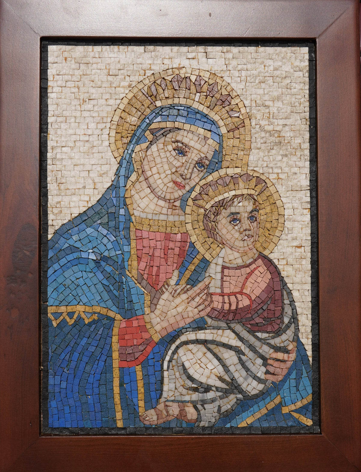 Intricate mosaic artwork depicting the Virgin Mary holding baby Jesus, featuring vibrant blue and gold tones.
