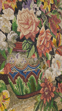 Intricate floral mosaic art featuring a vibrant pot adorned with colorful blooms and lush greenery, showcasing detailed craftsmanship.