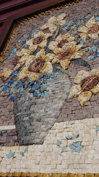Intricate mosaic artwork featuring a vase of sunflowers in warm tones — crafted from colorful stone pieces with detailed texture