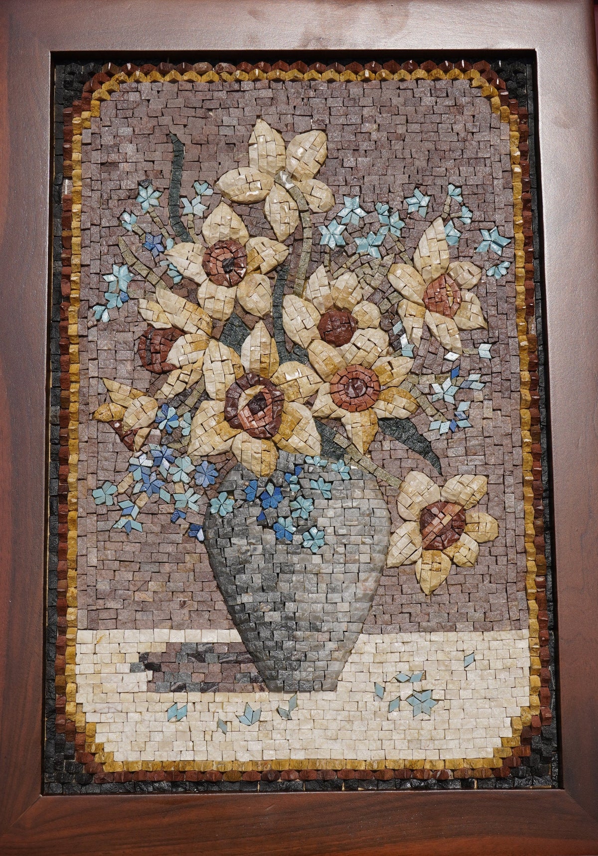 Intricate mosaic artwork featuring a vase of yellow flowers with blue accents — crafted from natural stone tiles.