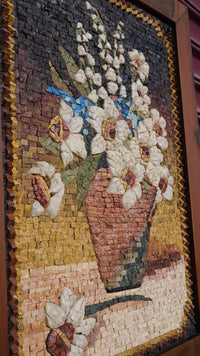 Intricate mosaic artwork featuring a floral arrangement in a textured vase — crafted with natural stone pieces in earthy tones.