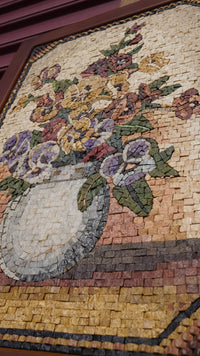 Intricate mosaic art featuring a floral arrangement in a vase, showcasing vibrant colours and textured tiles.