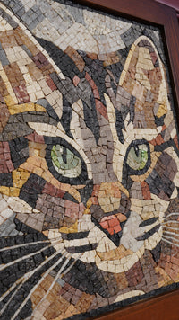 Intricate mosaic wall art featuring a cat's face with vibrant green eyes — crafted from varied natural stone pieces.